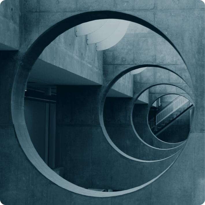 Architektonische Betonstruktur mit mehreren aneinandergereihten kreisförmigen Ausschnitten, im Hintergrund ist eine Treppe zu sehen.